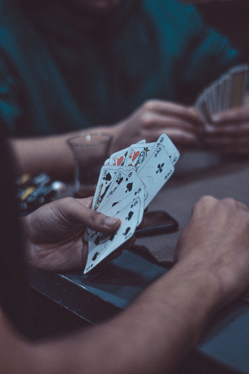 Eine Hand mit Spielkarten am Tisch